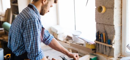 Self-employed carpenter planing wood on workbench