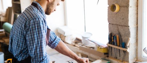 Self-employed carpenter planing wood on workbench