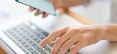 Business woman hand with Financial charts and mobile phone over laptop on the table .