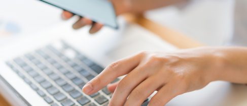 Business woman hand with Financial charts and mobile phone over laptop on the table .